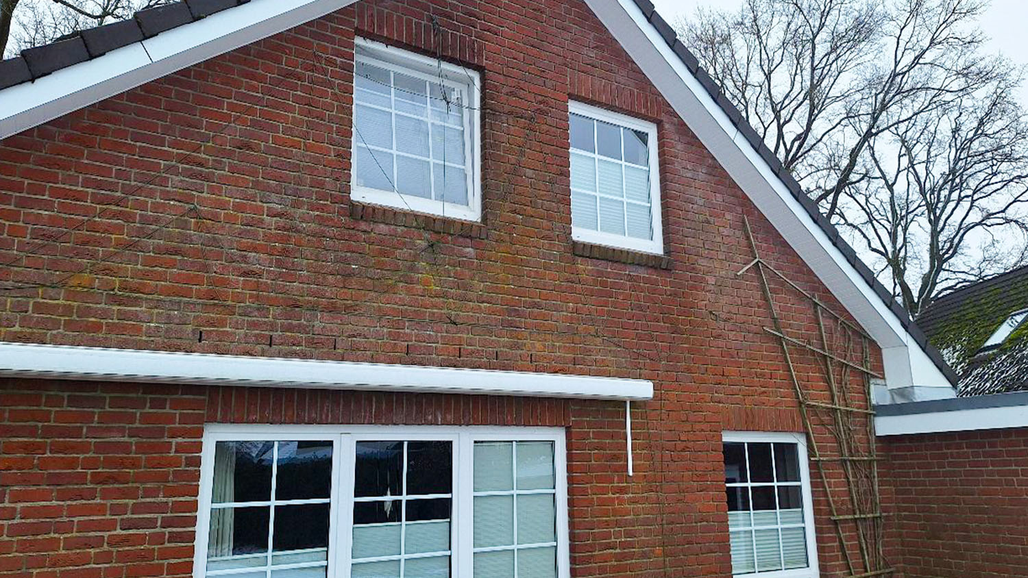 default Hausgiebel aus rotem Klinker mit Satteldach und weißen Fensterrahmen - Referenz