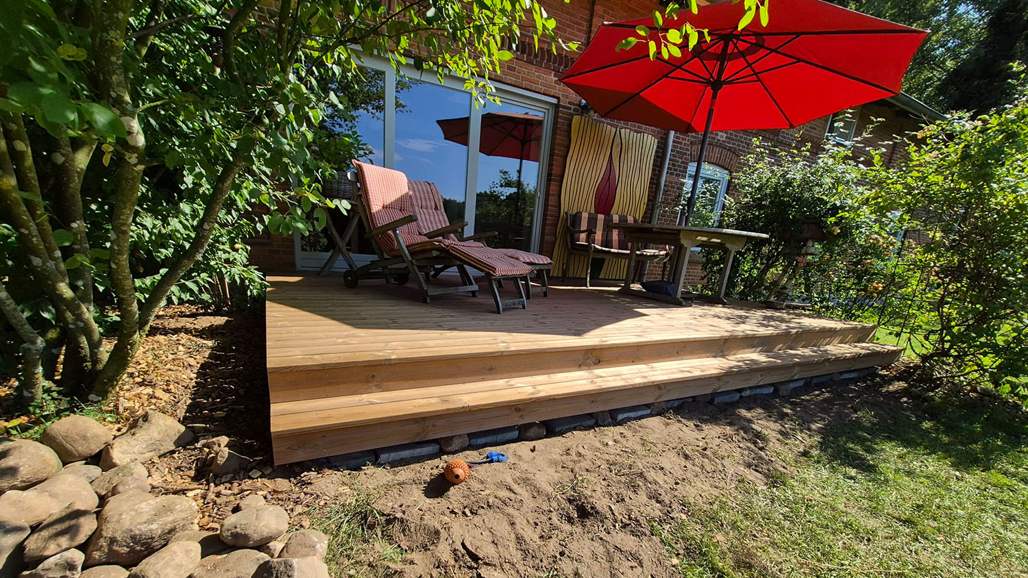 Holzterasse im Außenbereich mit Sitzmöbeln und Überdachung - Referenz